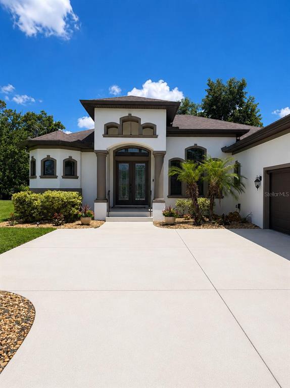 The exterior of a white stucco house features a prominent arched entryway and concrete driveway — 30 EGRET TRAIL, PALM COAST, FL