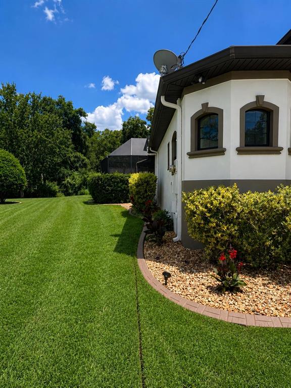 A side view of a house exterior featuring a manicured lawn and a landscaped garden bed — 30 EGRET TRAIL, PALM COAST, FL
