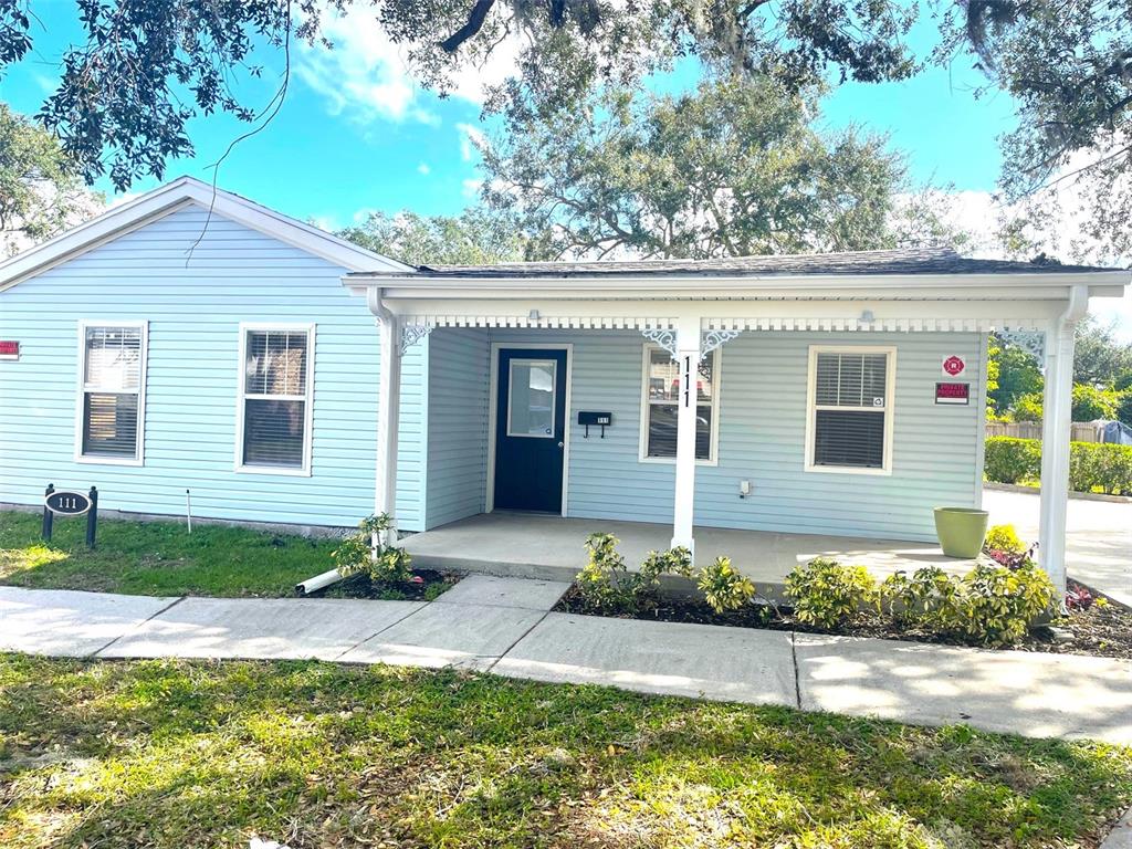 A light blue single-story house features a covered front porch and a dark entry door — 111 S RANDOLPH AVENUE, KISSIMMEE, FL
