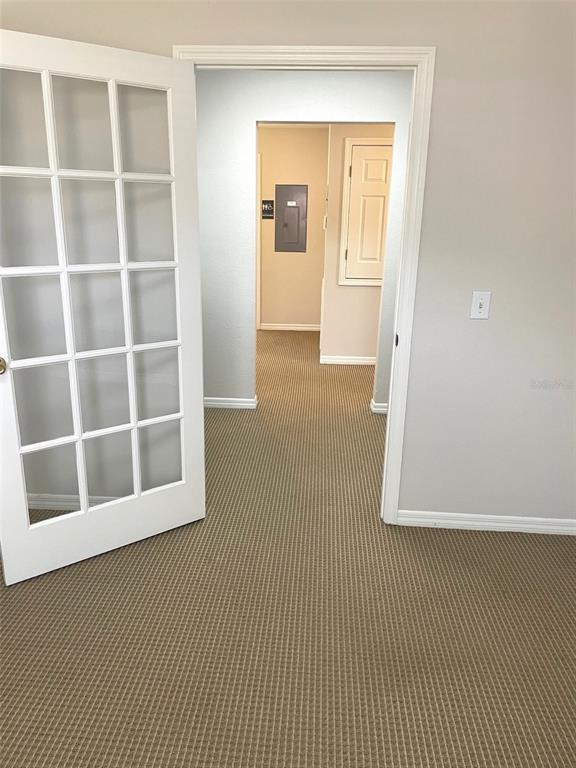 A room with beige carpet and a white French door leading to a hallway — 111 S RANDOLPH AVENUE, KISSIMMEE, FL