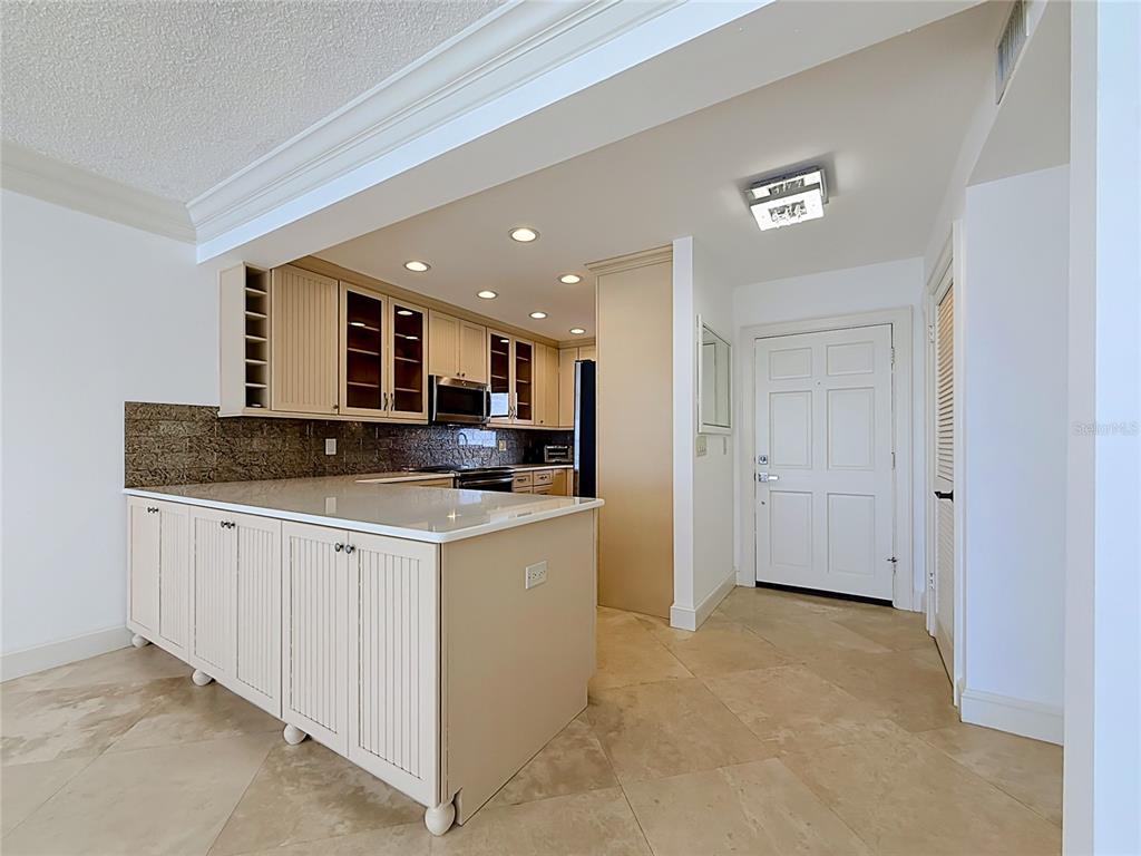 A kitchen features light-colored cabinetry, a stone countertop island, and tile flooring — 4950 GULF BOULEVARD UNIT 903, ST PETE BEACH, FL