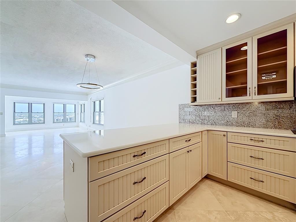 A kitchen with cream-colored beadboard cabinetry, granite countertops, and a view into an open room — 4950 GULF BOULEVARD UNIT 903, ST PETE BEACH, FL