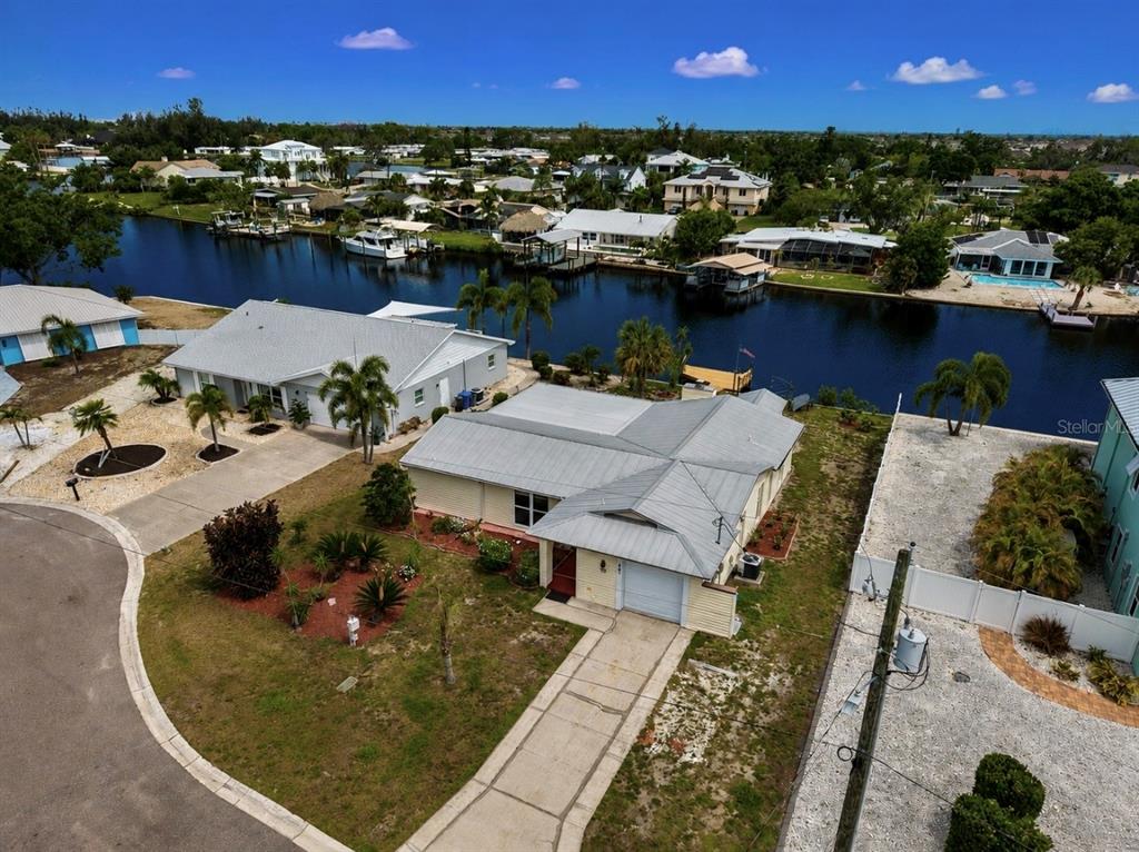 An aerial view shows a single-story house with a metal roof near a canal — 803 LEISEY CIRCLE, RUSKIN, FL