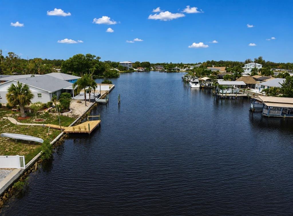 An aerial view shows a canal lined with houses, boat docks, and palm trees — 803 LEISEY CIRCLE, RUSKIN, FL