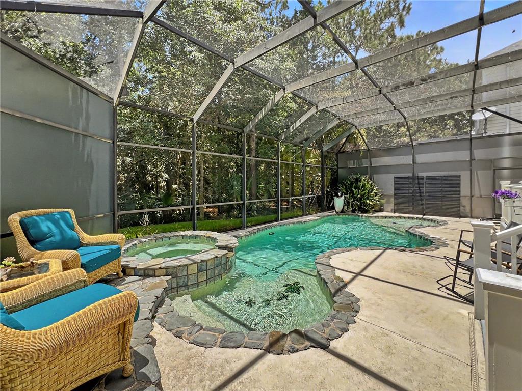 A screened-in patio features a swimming pool, a raised stone spa, and wicker lounge chairs — 816 RUNNER OAK STREET, CELEBRATION, FL