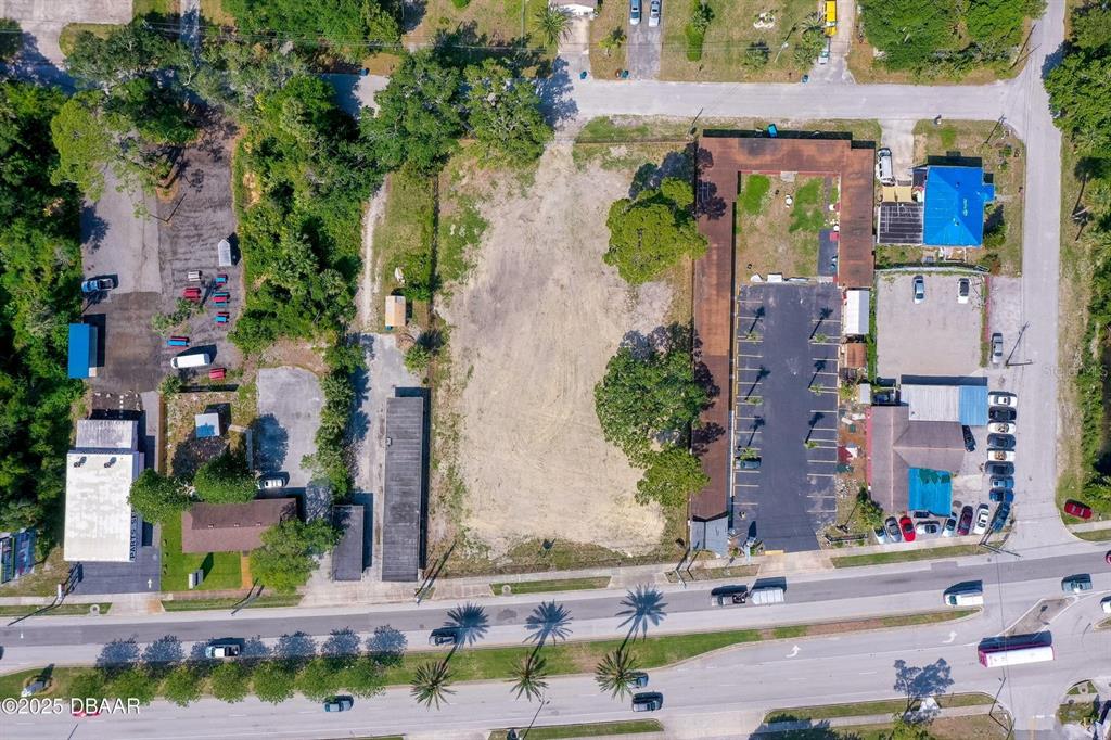 An aerial view shows a vacant lot situated between two commercial properties and a road — 670 S YONGE STREET, ORMOND BEACH, FL