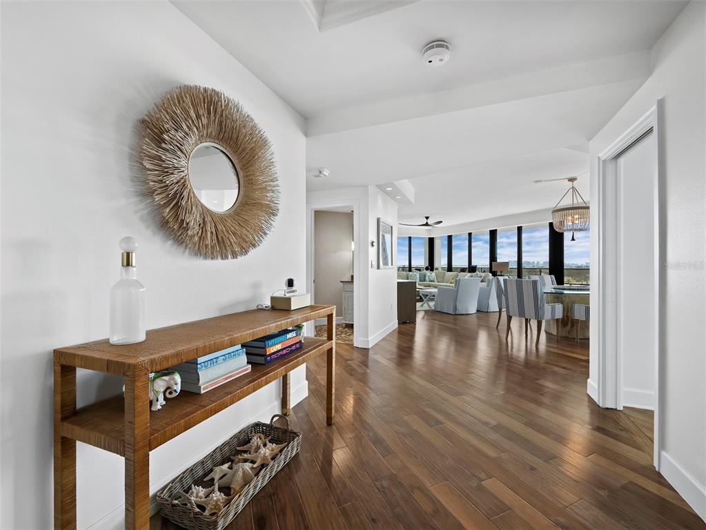 A hallway with hardwood floors leads to an open-concept living area with floor-to-ceiling windows — 535 SANCTUARY DRIVE UNIT A603, LONGBOAT KEY, FL