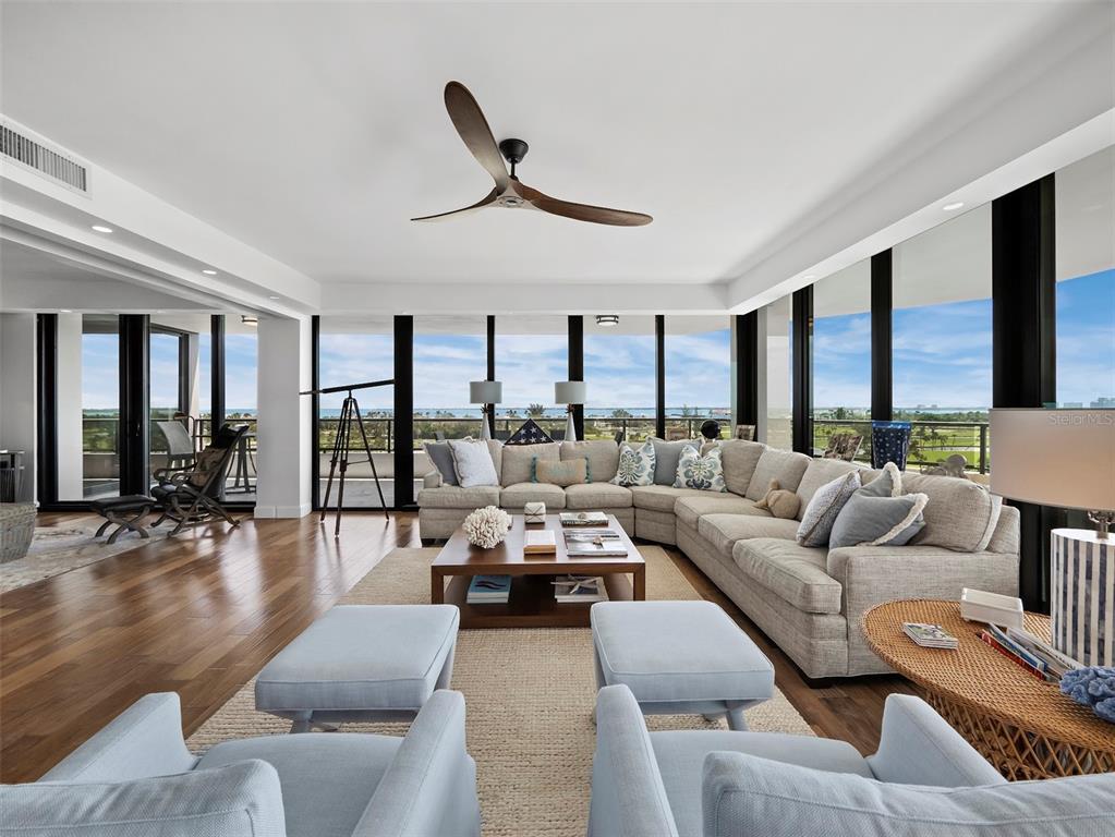 A bright living room features a large sectional sofa, light blue armchairs, and floor-to-ceiling windows — 535 SANCTUARY DRIVE UNIT A603, LONGBOAT KEY, FL