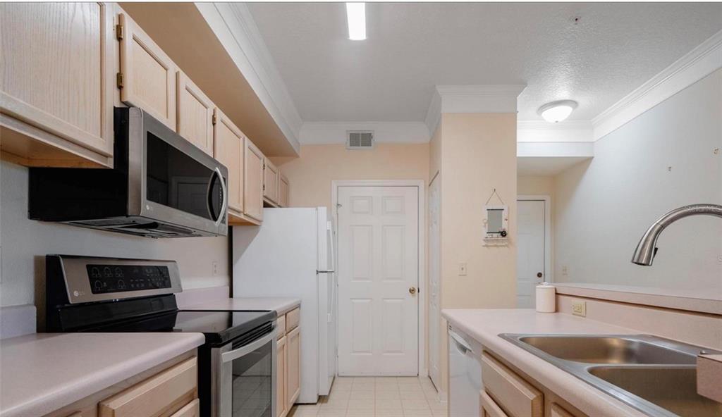 A kitchen features light wood cabinets, stainless steel appliances, a white refrigerator, and laminate countertops — 11490 VILLA GRAND UNIT 221, FORT MYERS, FL