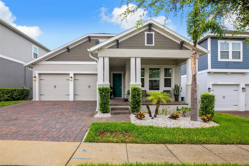 A single-story house with a two-car garage, covered front porch, and landscaped front yard — 15009 LEBEAU LOOP, WINTER GARDEN, FL