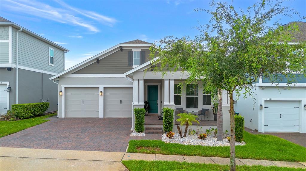 A single-story house with a two-car garage, a covered front porch, and a landscaped yard — 15009 LEBEAU LOOP, WINTER GARDEN, FL