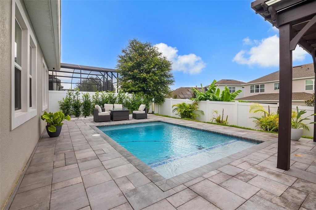 A backyard features a swimming pool, a pergola with dining furniture, and a covered patio — 15009 LEBEAU LOOP, WINTER GARDEN, FL