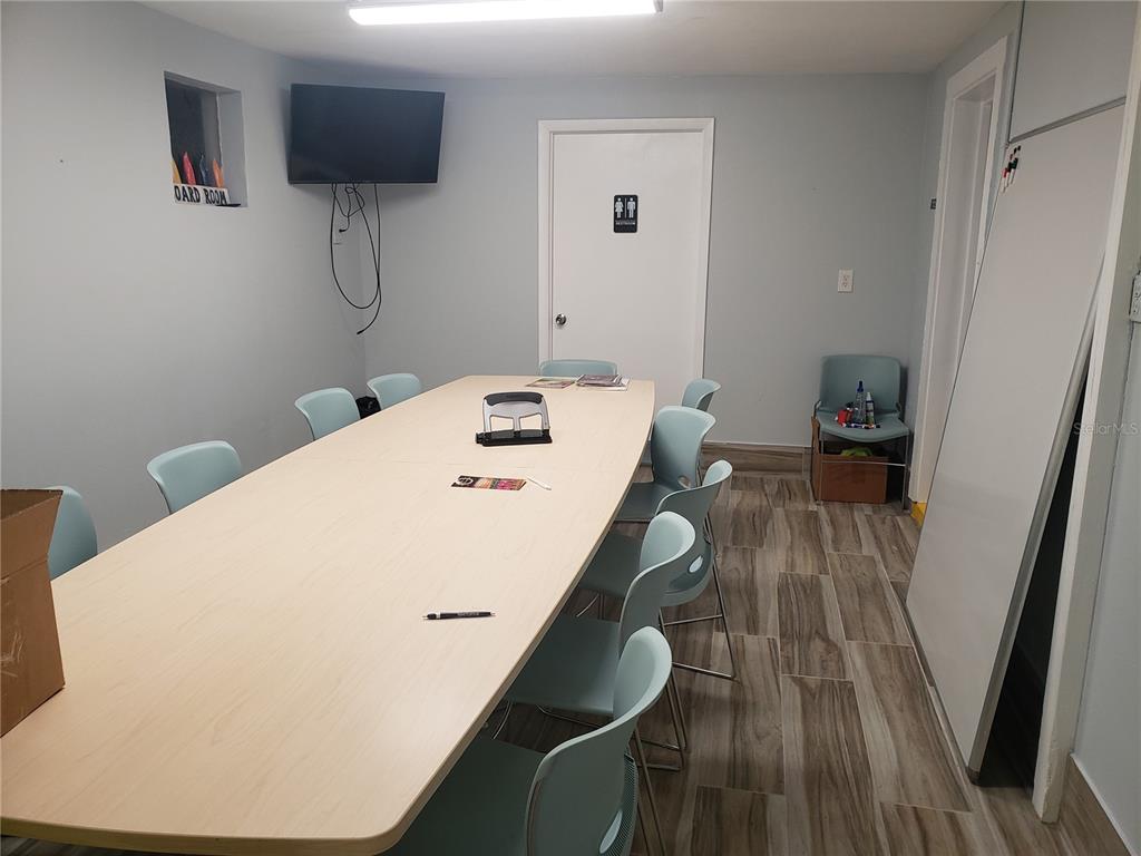 A conference room features a long table, light blue chairs, wood-look flooring, and a television — 201 W SHELL POINT ROAD, RUSKIN, FL