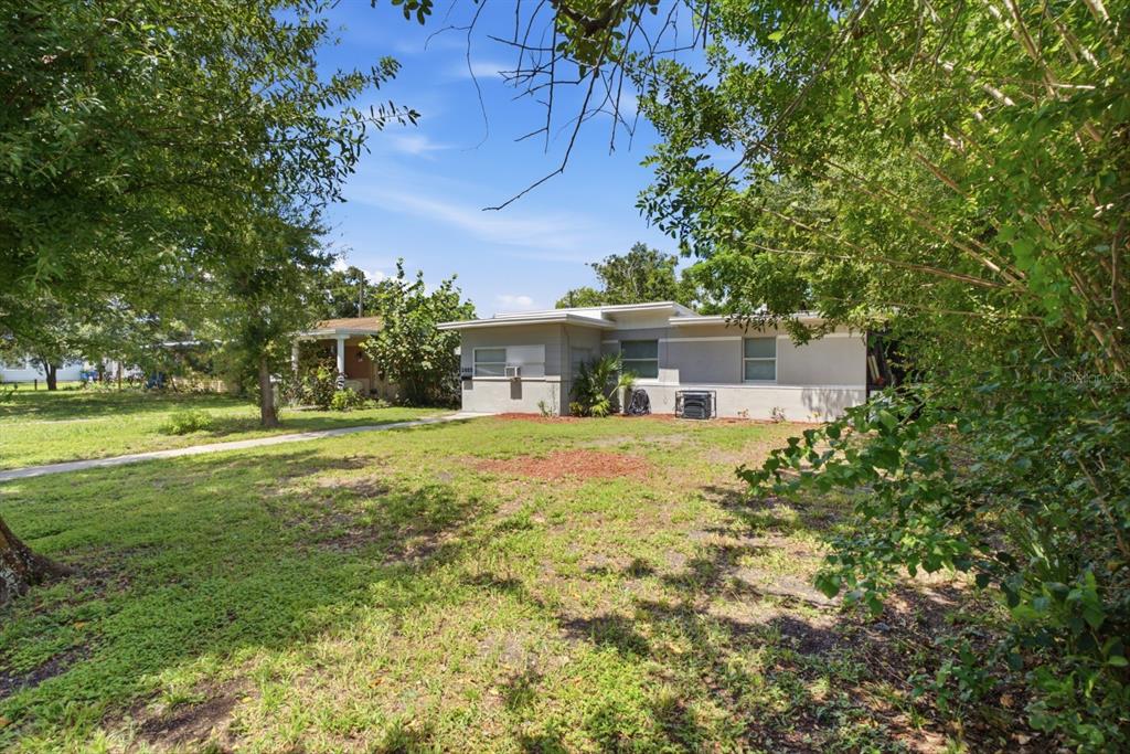 A single-story house with a flat roof sits on a grassy lot with mature trees — 2855 37TH AVENUE N, ST PETERSBURG, FL