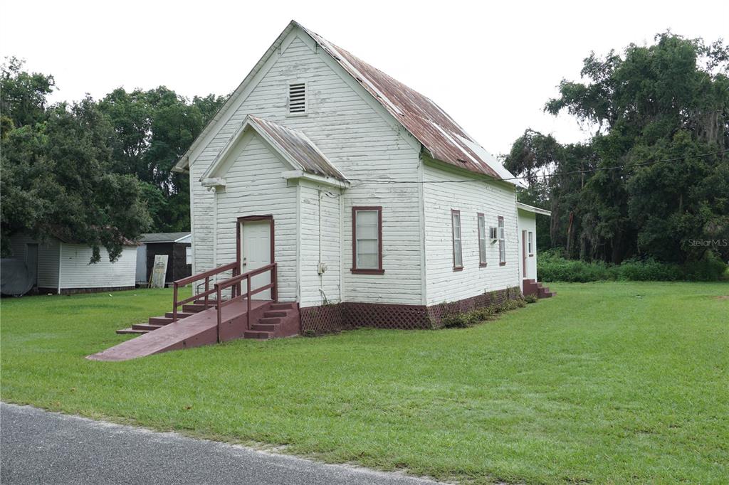 A white, wood-sided church building with a metal roof and a wheelchair ramp stands outside — 12701 NW 38TH AVENUE, REDDICK, FL