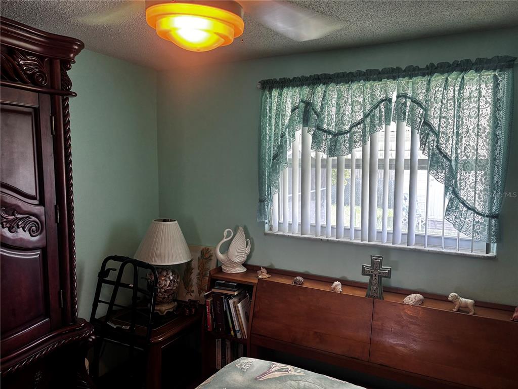 A bedroom features a wooden armoire, a desk with books, a window with curtains, and decor — 9040 CHATAM LANE, PORT RICHEY, FL