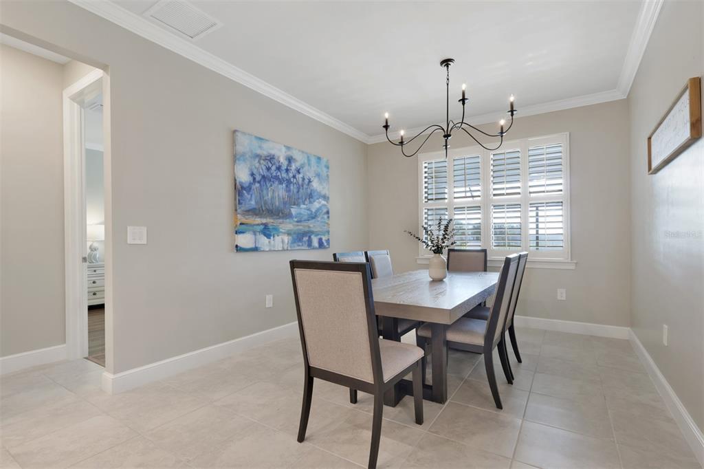 A dining room features a wooden table, upholstered chairs, a chandelier, and a large painting — 3425 HAMPTON BOULEVARD, ALVA, FL