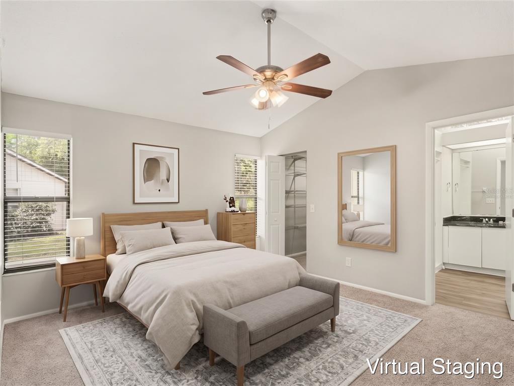 A bedroom with beige carpet, light gray walls, a ceiling fan, and an attached bathroom — 8211 COUNTRY OAKS COURT, SARASOTA, FL