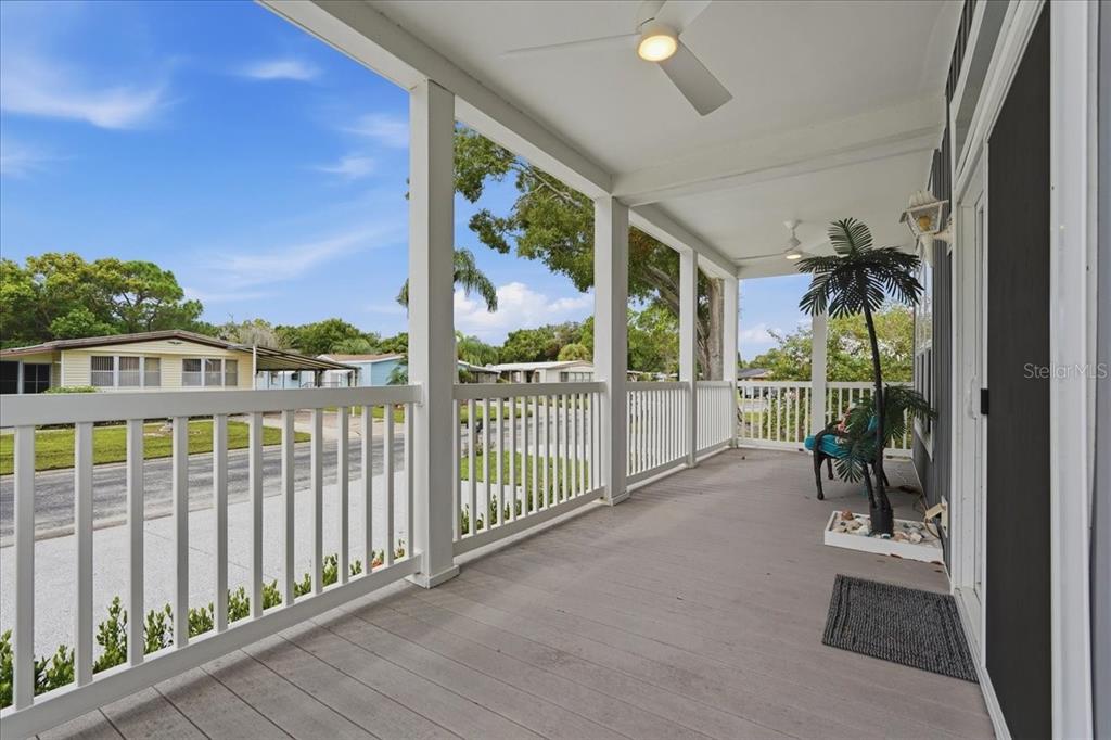 A covered porch features white railings, a ceiling fan, and a view of neighboring homes — 8903 SHELDON WEST DRIVE, TAMPA, FL