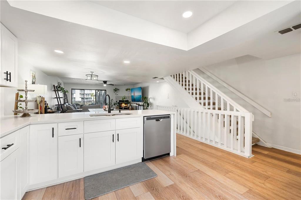 A modern kitchen features white cabinets, quartz countertops, a breakfast bar, and a window view — 745 PINELLAS BAYWAY S UNIT 106, TIERRA VERDE, FL