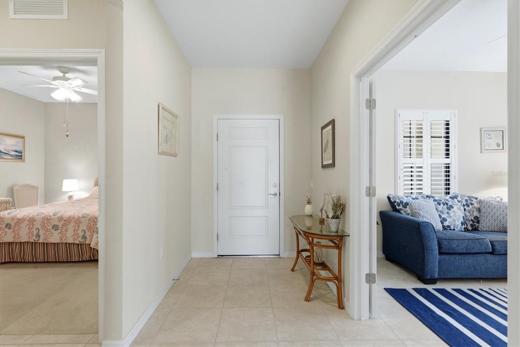 A tiled entryway features a white front door, a console table, and adjacent room openings — 1359 BACKSPIN DRIVE, ENGLEWOOD, FL