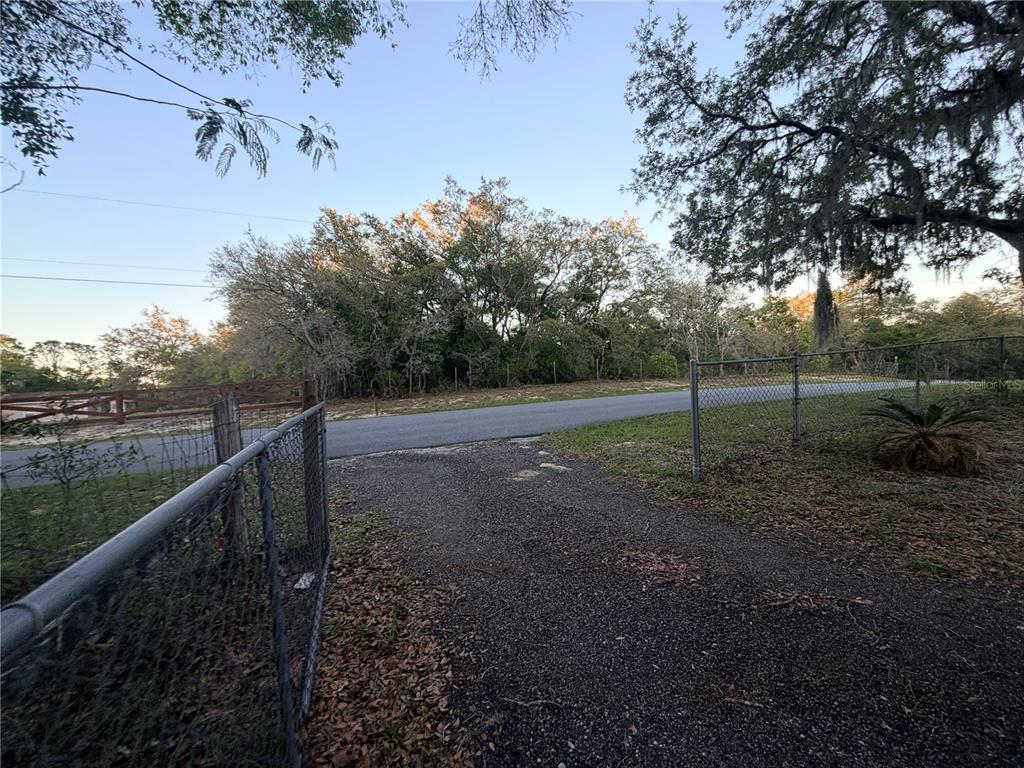 A single-story manufactured home sits on a large, grassy lot with a gravel driveway — 4880 N HIGHLAND PARK DRIVE, HERNANDO, FL