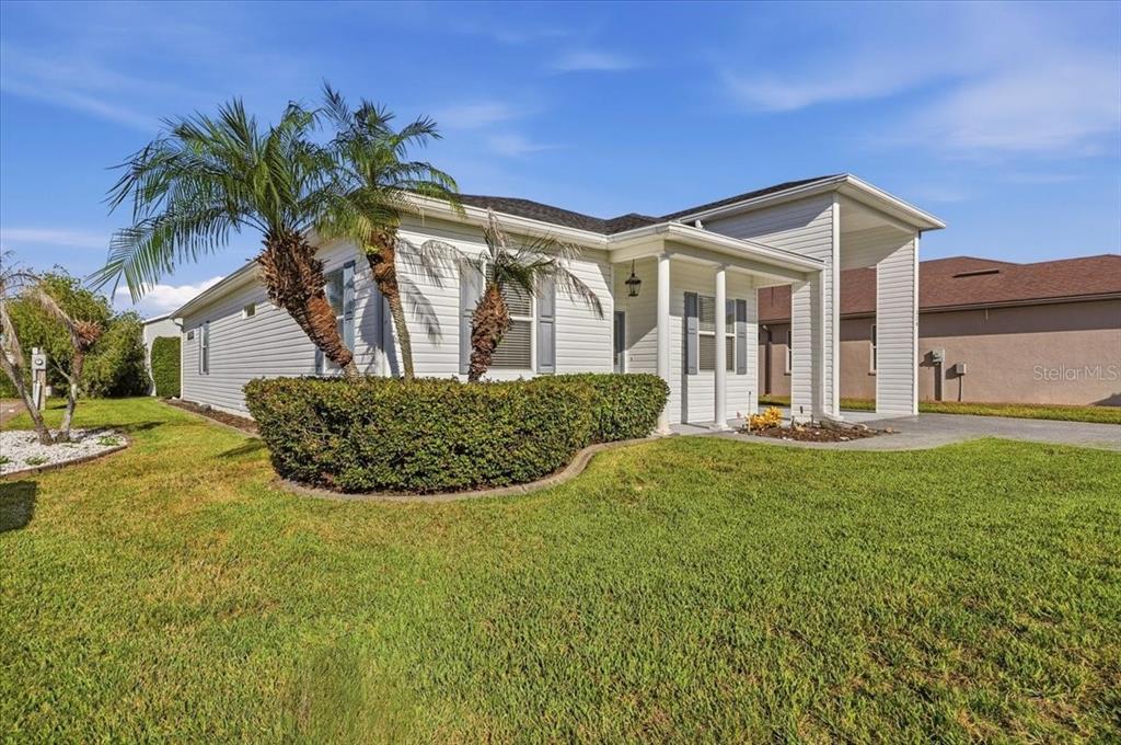A white, single-story house with a covered entryway and palm trees in the front yard — 328 MOTORCOACH DRIVE S, POLK CITY, FL