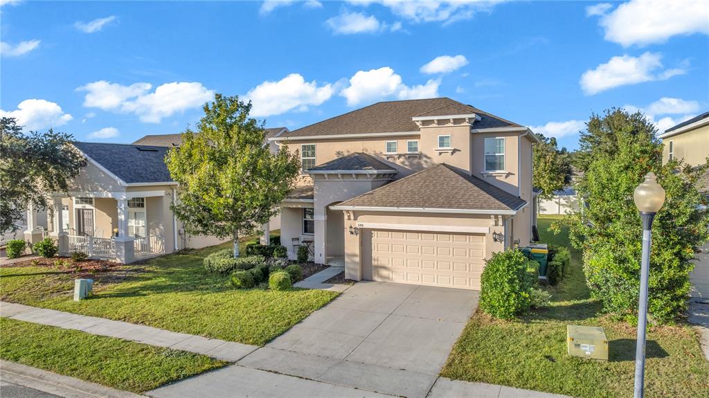 A two-story tan suburban house with a two-car garage and a front yard — 3301 BETHPAGE LOOP, MOUNT DORA, FL
