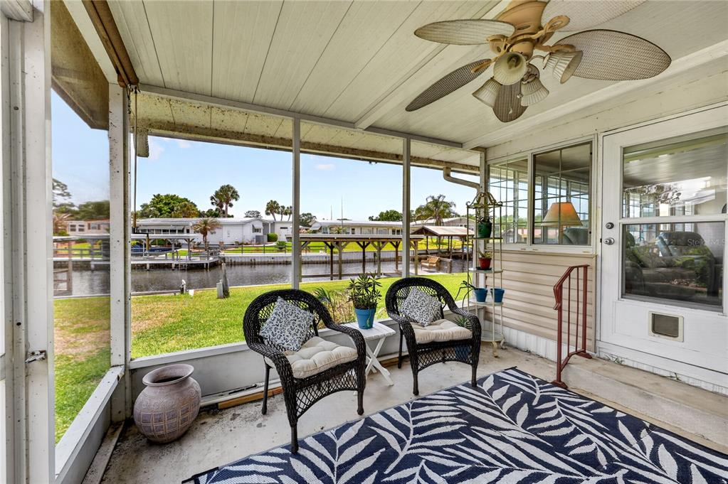 A wooden boat lift with a metal roof extends over a canal between two houses — 957 TODD WAY, TAVARES, FL