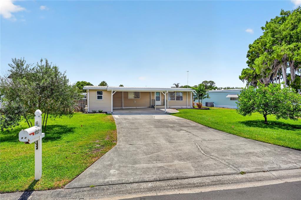 A wooden boat dock with a covered slip and a seating area sits on a canal — 957 TODD WAY, TAVARES, FL