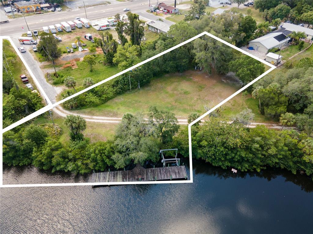 An aerial view shows a waterfront lot with a wooden dock and trees — 102 DICKMAN DRIVE SW, RUSKIN, FL