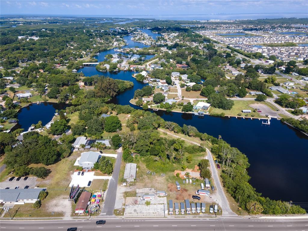 An aerial view shows a waterfront property with a parking lot and surrounding residential area — 102 DICKMAN DRIVE SW, RUSKIN, FL