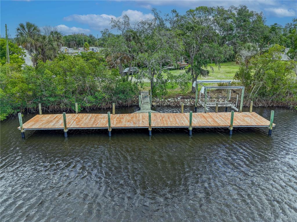 An aerial view shows a long wooden dock extending into a body of water — 102 DICKMAN DRIVE SW, RUSKIN, FL