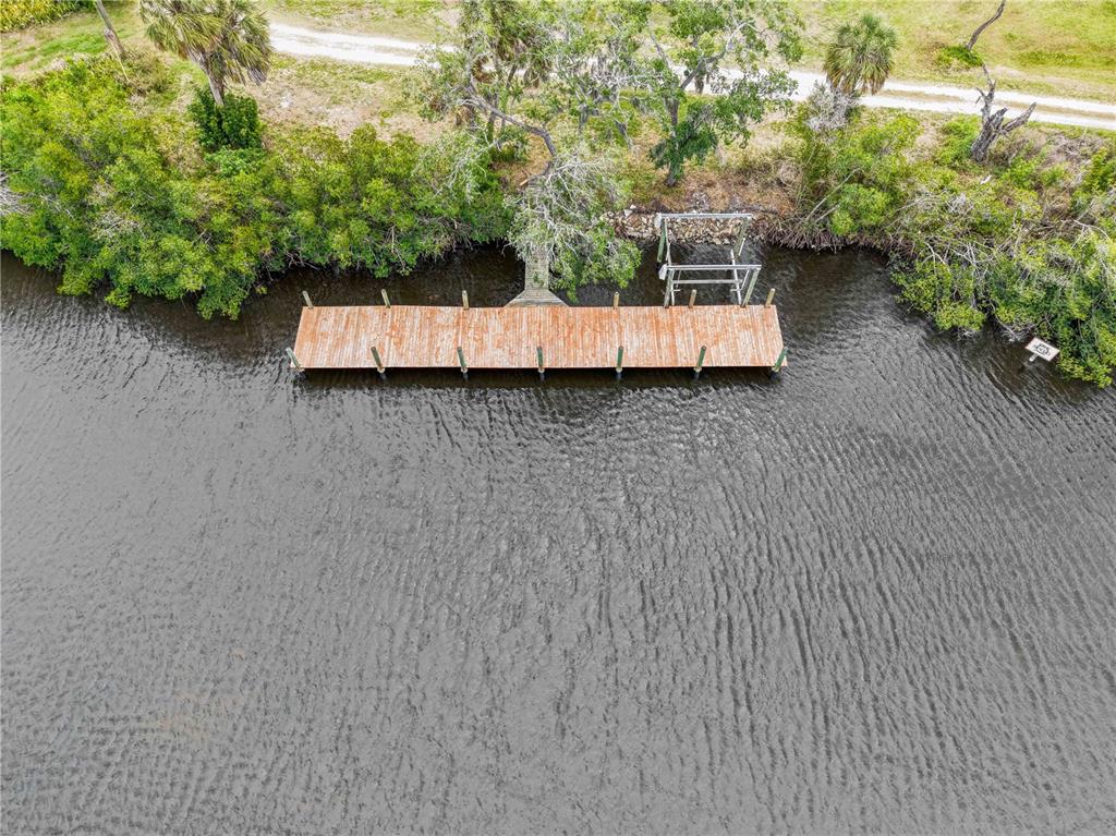 An aerial view shows a wooden dock extending into a river from a wooded shoreline — 102 DICKMAN DRIVE SW, RUSKIN, FL