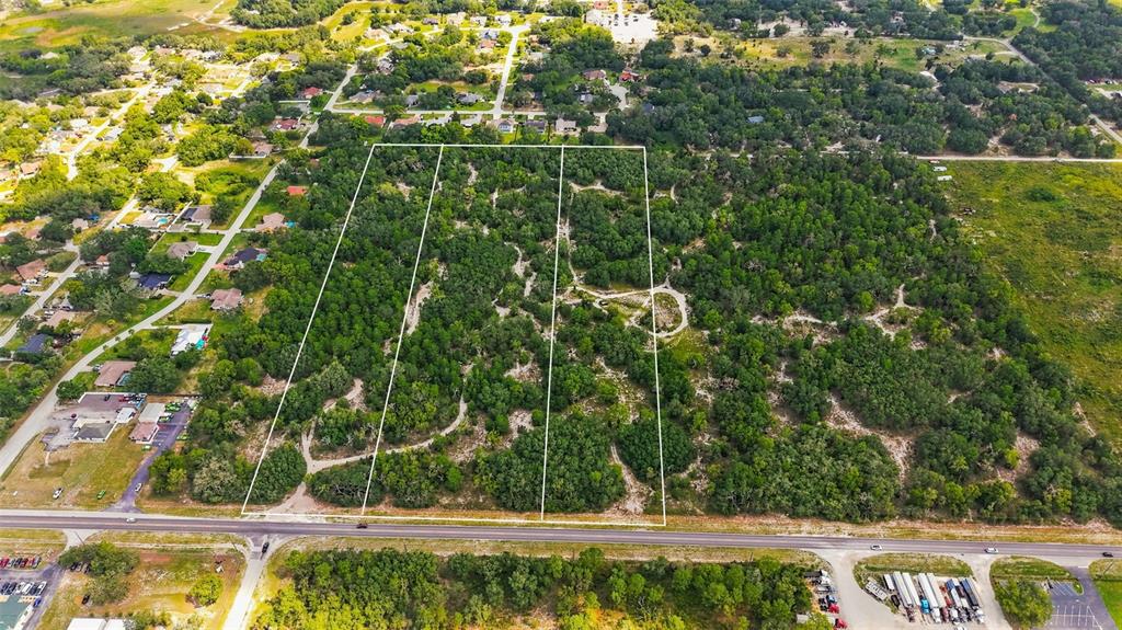 An aerial view shows a large, wooded rectangular plot of land bordered by a road — 8439 COUNTY LINE ROAD, SPRING HILL, FL