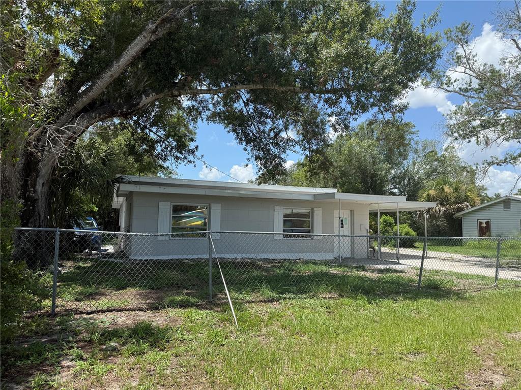 A single-story gray house with a metal roof sits behind a chain-link fence — 401 CITRUS AVENUE, ARCADIA, FL