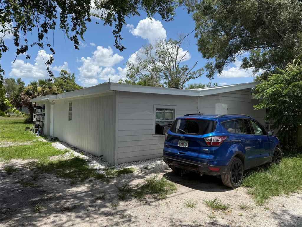 A blue SUV is parked on a dirt lot next to a light-colored exterior wall — 401 CITRUS AVENUE, ARCADIA, FL