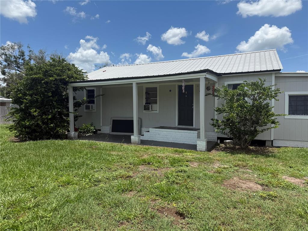 A single-story house with a metal roof and a covered front porch sits on grass — 401 CITRUS AVENUE, ARCADIA, FL