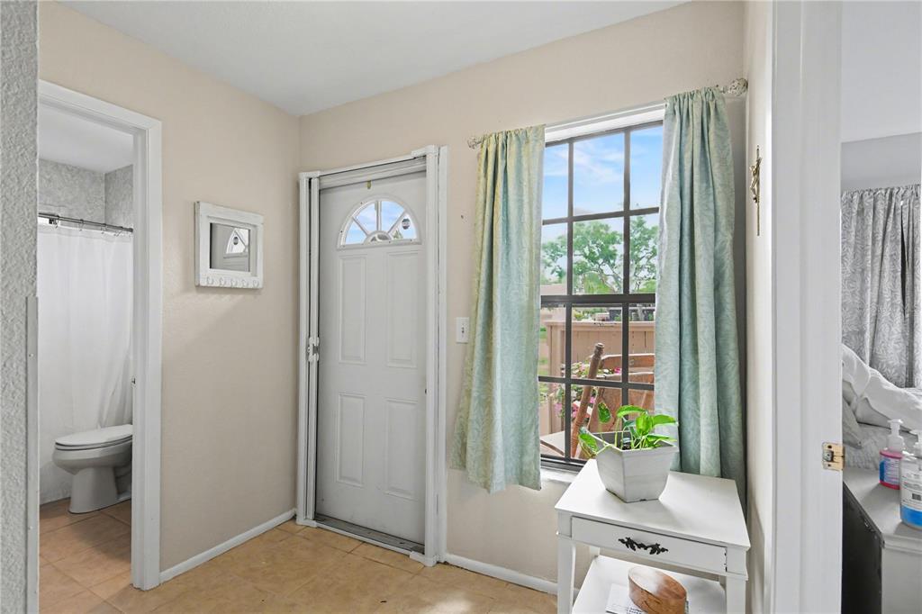 An entryway features a white door, a window with light curtains, and a tiled floor — 5401 BRASSY LOOP, NORTH PORT, FL