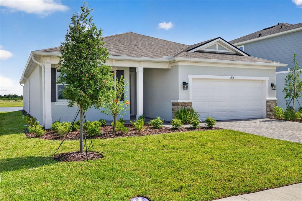 A single-story house with a light-colored exterior, a two-car garage, and a landscaped front yard — 13136 OXEYE LANE, PARRISH, FL