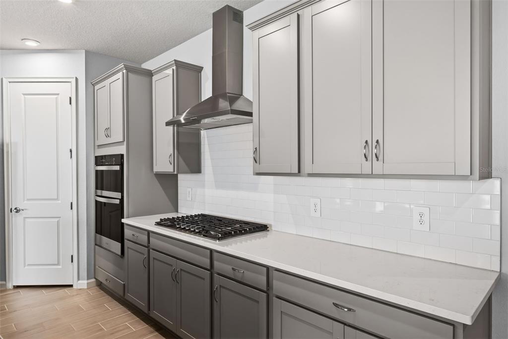 A kitchen features grey cabinets, white subway tile backsplash, a gas cooktop, and stainless appliances — 13136 OXEYE LANE, PARRISH, FL