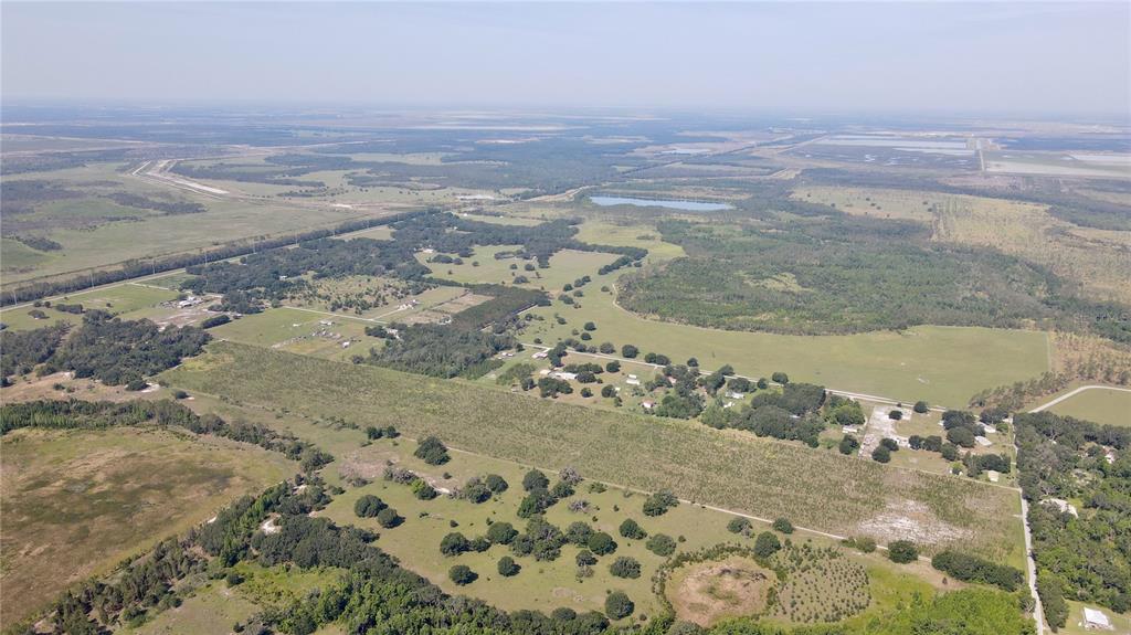 An aerial view shows a large, rural landscape with scattered trees, pastures, and small buildings — ALBRITTON, LITHIA, FL