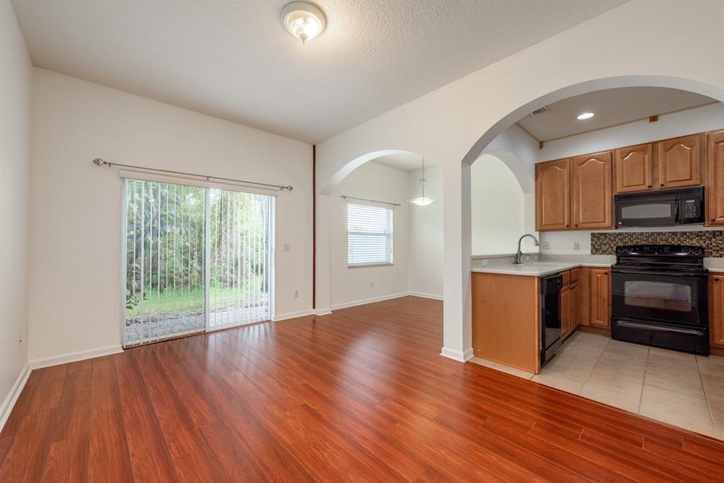A dining area with wood flooring and sliding glass doors next to a kitchen — 11935 GREAT COMMISSION WAY, ORLANDO, FL