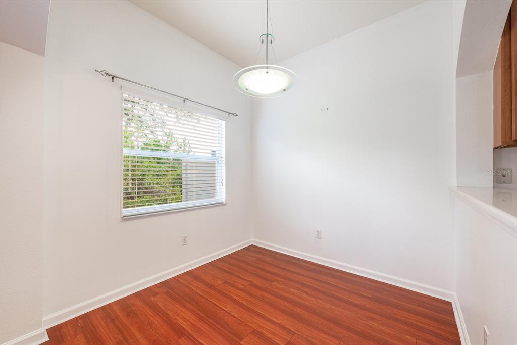 An empty dining area features white walls, wood-look flooring, a window with blinds, and a pendant light — 11935 GREAT COMMISSION WAY, ORLANDO, FL