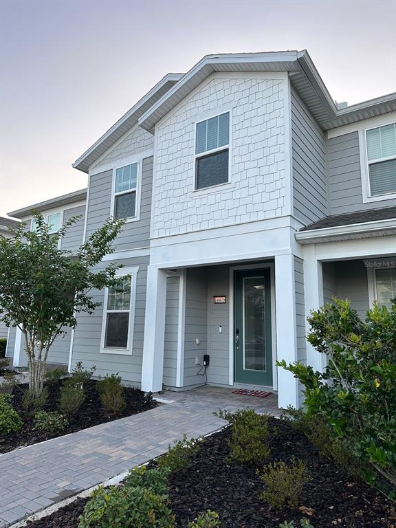 A two-story house exterior features gray horizontal siding, white trim, and a paved walkway — 14475 SAPELO BEACH DRIVE, ORLANDO, FL