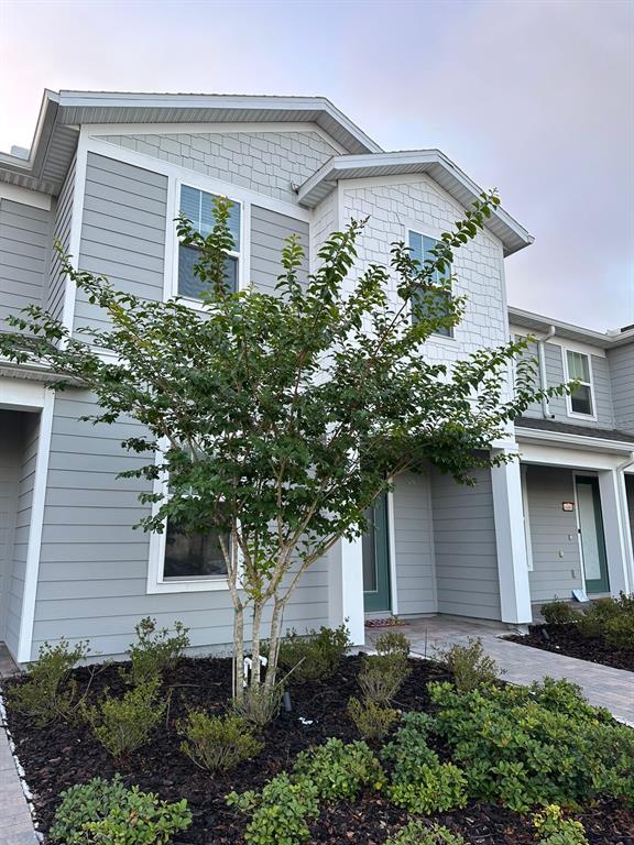 A multi-story gray townhouse exterior features a central tree and landscaped garden beds — 14475 SAPELO BEACH DRIVE, ORLANDO, FL