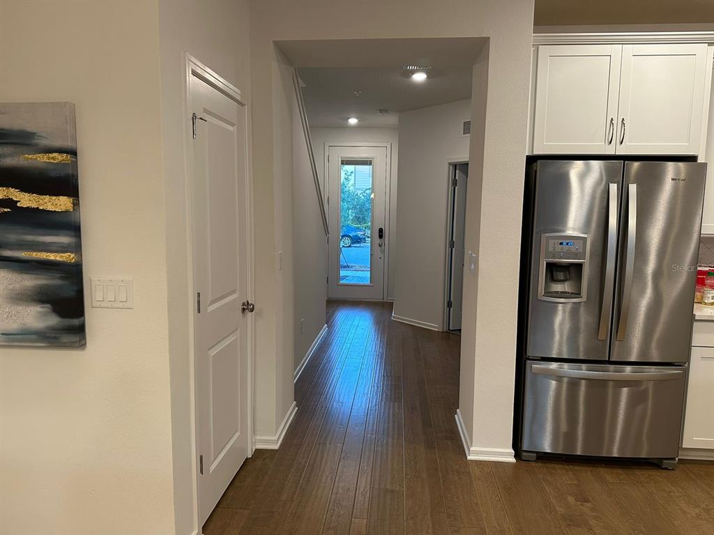 A hallway with wood flooring leads to an exterior door between a kitchen and closet — 14475 SAPELO BEACH DRIVE, ORLANDO, FL