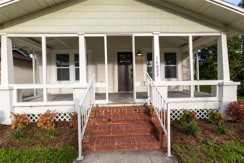 A front view of a house featuring a screened-in porch with brick steps — 14022 4TH STREET, DADE CITY, FL