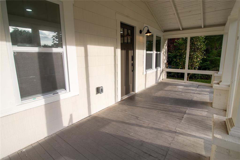 A covered, screened-in wooden porch features a dark front door and white siding — 14022 4TH STREET, DADE CITY, FL