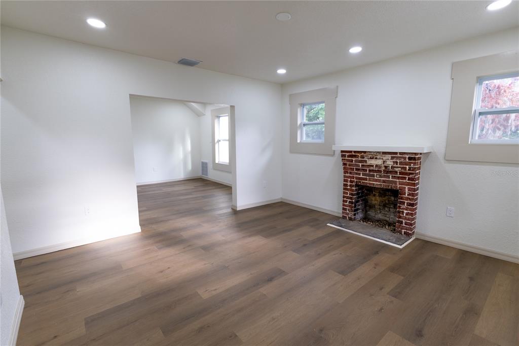 A living room features wood-look flooring, white walls, recessed lighting, and a brick fireplace — 14022 4TH STREET, DADE CITY, FL